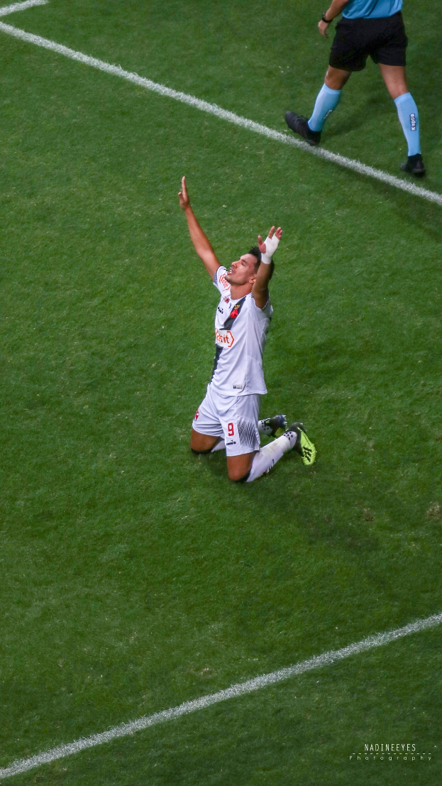 Ein Fussballspieler in einem Sportoutfit kniet auf dem Boden und streckt die Arme aus.