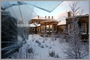 Ein Haus mit Schnee auf dem Dach und schneebedeckten Pflanzen am Boden.