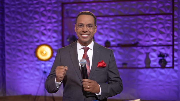 Stephen Colbert, Moderator von 'The Daily Show with Trevor Noah', steht auf einer Bühne und hält ein Mikrofon in der Hand, trägt einen Anzug, Krawatte und eine Brille.