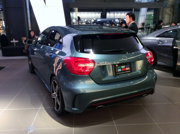 Ein Mercedes-Benz A-Klasse Fließheck in Glossy Black mit Chromakzenten, niedriges Profil, breite Basis, markantes Grill und Aluminiumräder, umgeben von Menschen.