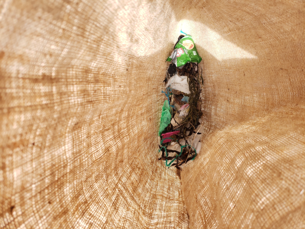 Nahaufnahme eines zerknüllten Papiers auf einem Tisch mit einem Jutestoff im Hintergrund, wahrscheinlich recycelter Abfallmaterial.