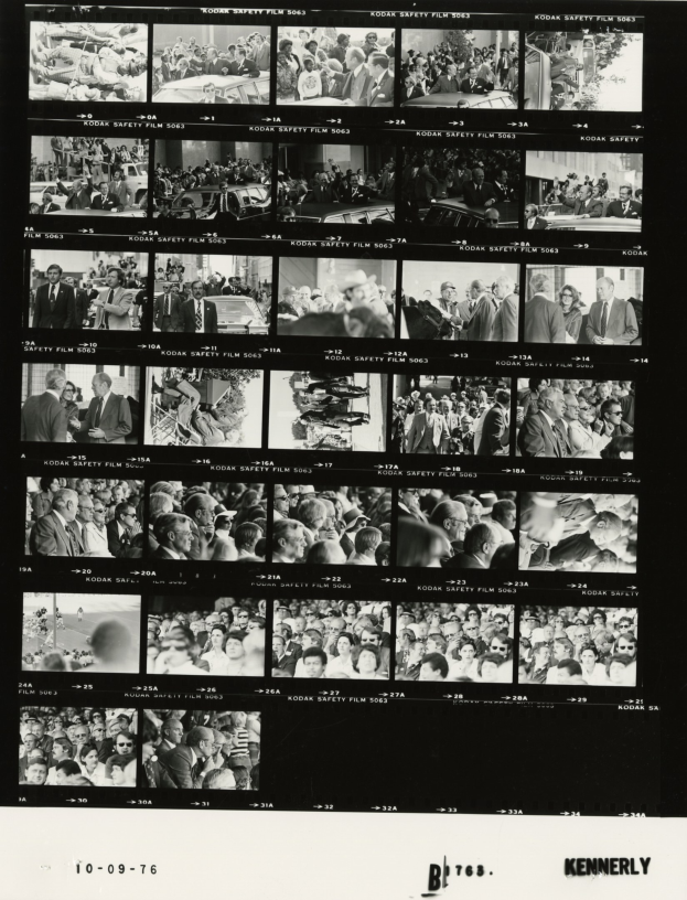 Schwarzes und weißes Foto einer vielseitigen Menge, die fröhlich um einen Fernseher versammelt ist, mit sichtbarem Text unten.