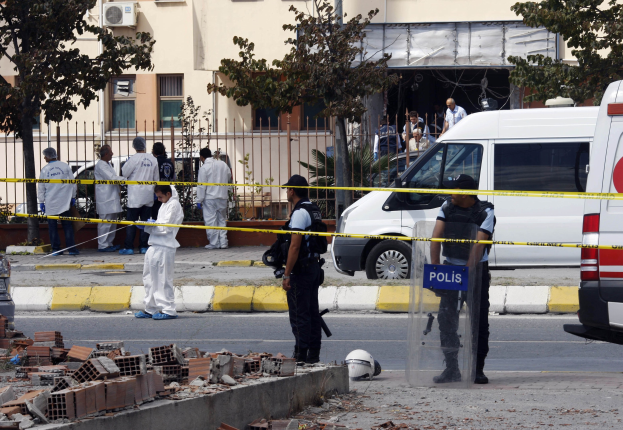 Gruppe von Polizisten vor einem Gebäude mit verstreuten Trümmern, darunter Ziegelsteine und ein Helm, wahrscheinlich nach einer Bombenexplosion in Mexiko-Stadt.