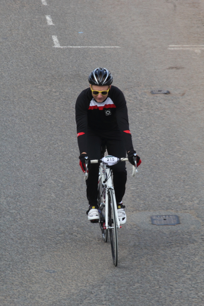 Eine Person mit Helm und Brille fährt ein Fahrrad auf einer Straße.