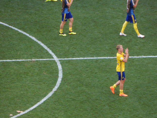 Gruppe von Männern in Fußballtrikots, die auf einem Feld nach einem Spiel klatschen.