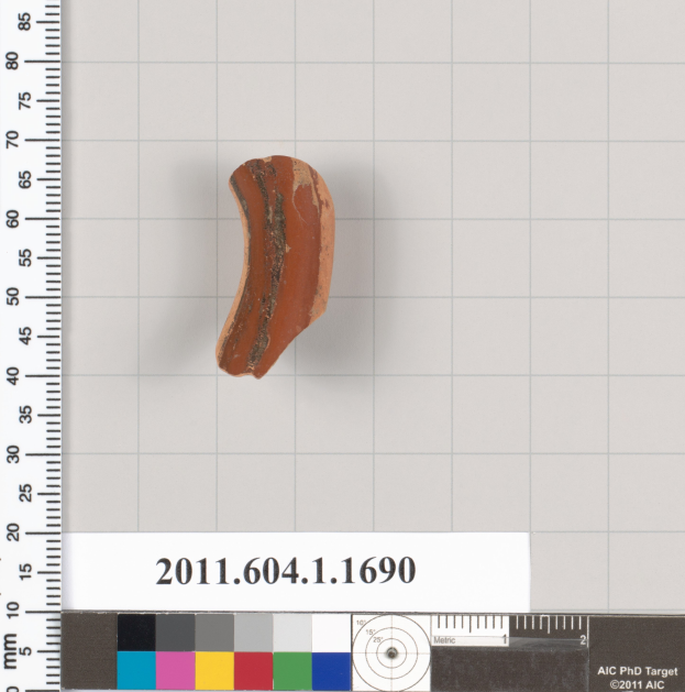 Ein kleines Tonstück wird auf einem Lineal mit einer Waage und einer Farbskala daneben platziert.