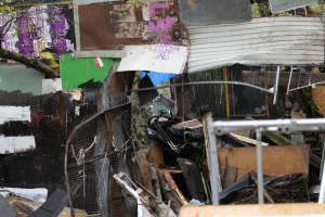 Ein Haufen Müll liegt vor einem Gebäude mit Graffiti an den Wänden, umgeben von Bäumen und anderen Gegenständen.