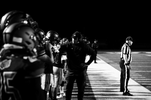 Schwarzes Foto von Fußballspielern in Helmen und Sneakers auf einem Feld.