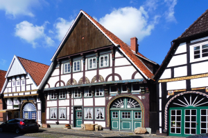 Reihe von Fachwerkhäusern in Heidelbergs Altstadt mit Fahrzeugen auf der Straße und einem bewölkten Himmel.