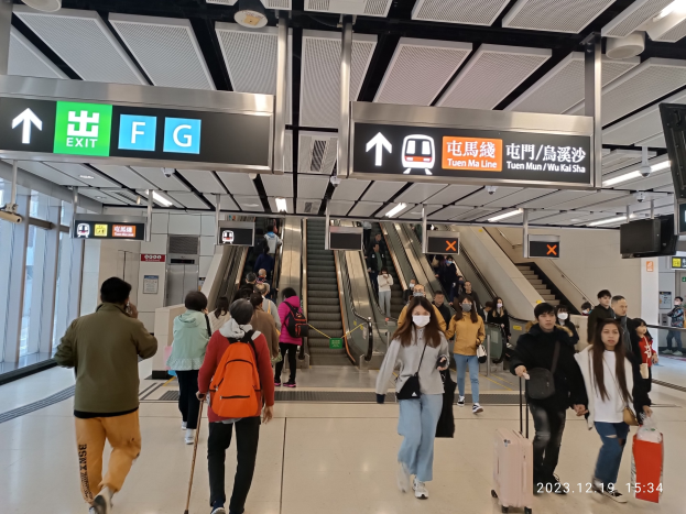 Menschen mit Gepäck durch einen geschlossenen Flughafen gehen, Rolltreppen, Informationsanzeigen, Deckenleuchten und Glaswände im Hintergrund sichtbar.