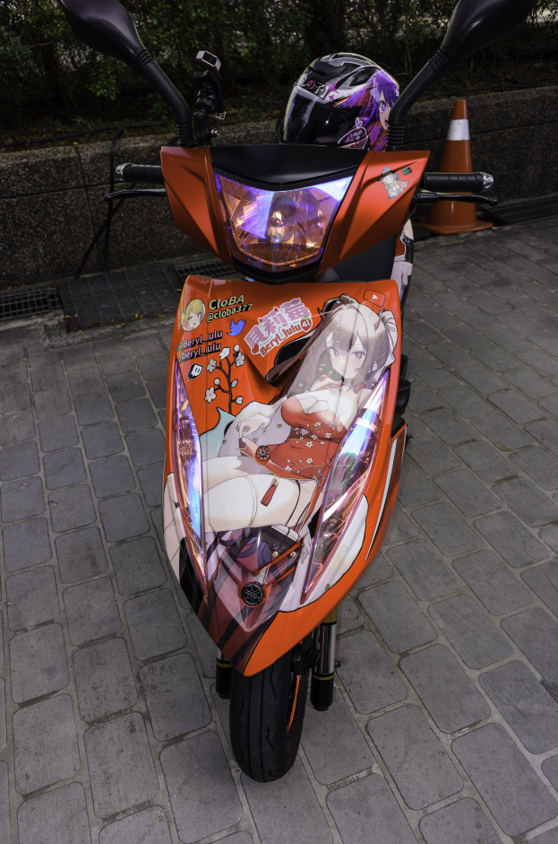 Ein oranges E-Scooter mit Helm darauf auf einer Straße geparkt, mit einem Verkehrskegel, einer Wand und Bäumen im Hintergrund.