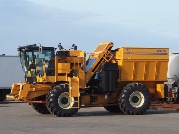 Großer gelber Volvo L220 Radlader vor einem weißen Container auf einer Straße mit einem klaren blauen Himmel geparkt