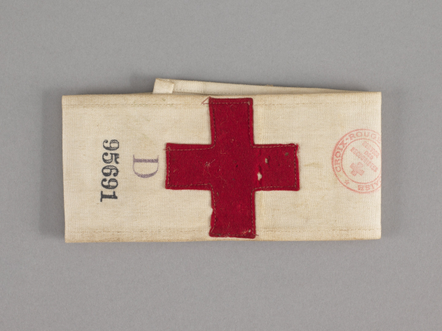 Ein rotes Kreuz-Ersthelfer-Set mit einem Text- und Stempel-aufweisendem Stoffbeutel, der auf einer Oberfläche liegt.