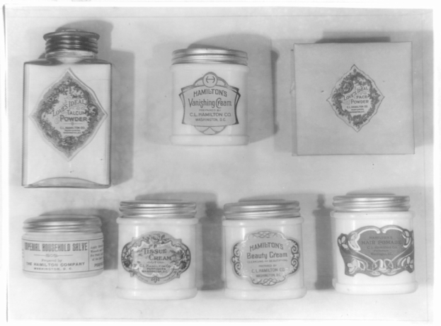 Schwarz-weiß-Foto eines Regals mit ordentlich angeordneten Sahnetöpfchen, jedes mit verschiedenen Typen beschriftet.