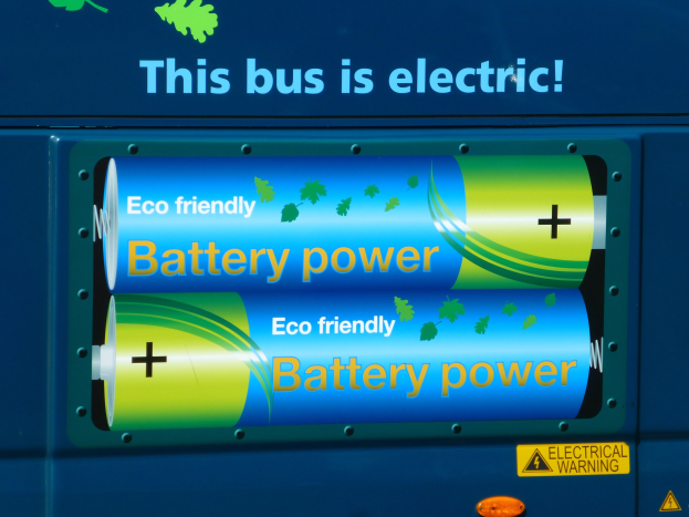 Blauer Elektrobus mit "Dieser Bus ist elektrisch"-Schriftzug und zwei sichtbaren seitlich angebrachten Batterien.