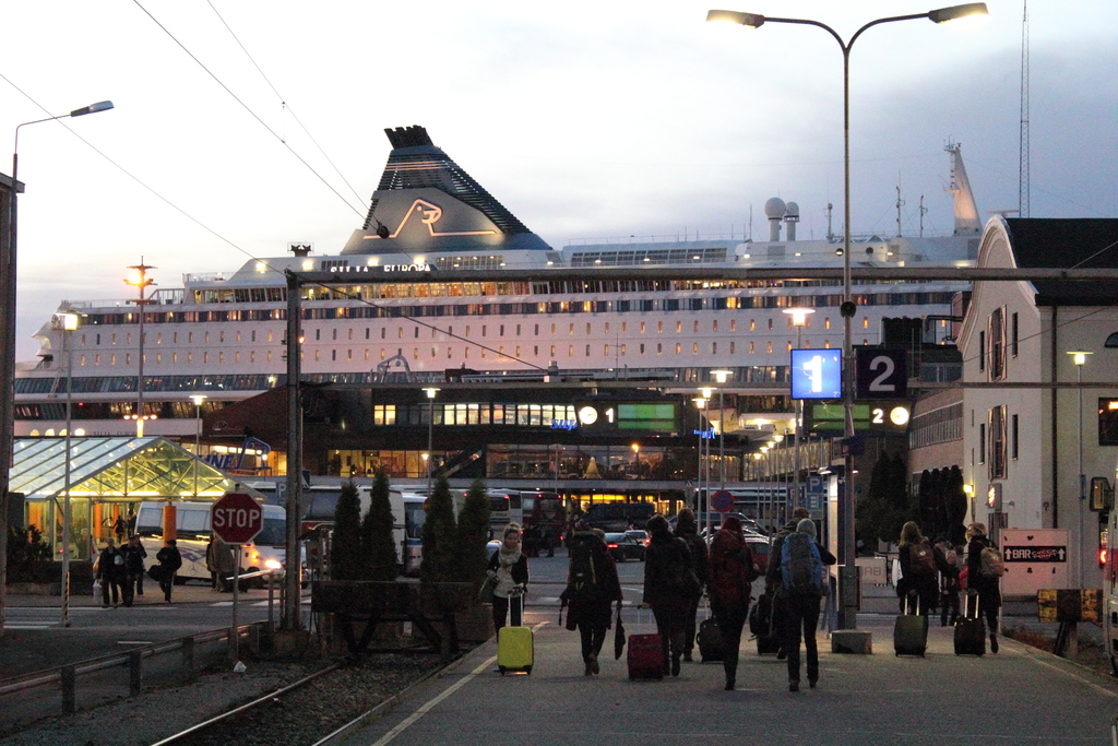 Eine volle Straße mit Menschen, die Taschen tragen und an Pfählen und Gebäuden vorbeigehen.