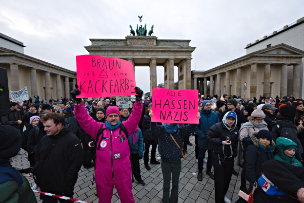 Gruppe von Demonstranten protestiert vor dem Brandenburger Tor in Berlin, hält Schilder gegen die Anti-Nazi-Bewegung der deutschen Regierung.