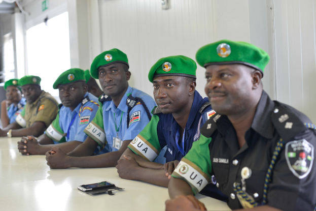 Gruppe von Polizisten bei einer Schulung am Tisch sitzend, mit Mobiltelefonen und anderen Gegenständen auf dem Tisch.