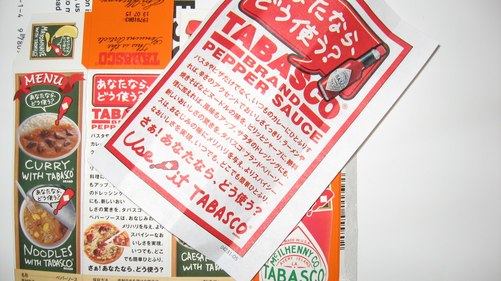 Ein Prospekt, das Pfeffersoße bewirbt, mit einem darunter liegenden Blatt, auf dem verschiedene Currys beworben werden.