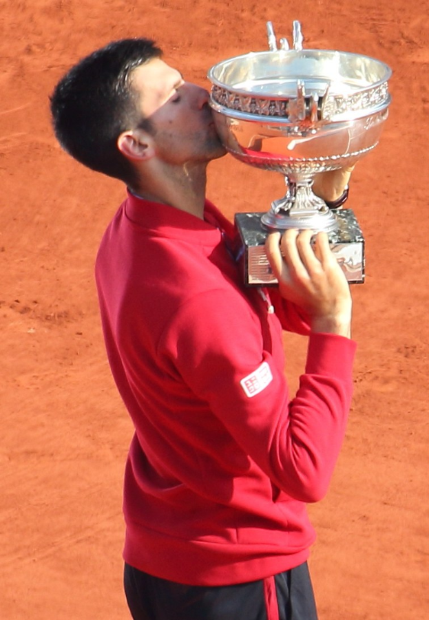 Novak Djokovic feiert mit dem French Open-Pokal nach Sieg gegen Rafael Nadal im Herrensingelfinale, hält und küsst den Pokal mit triumphierendem Gesichtsausdruck.