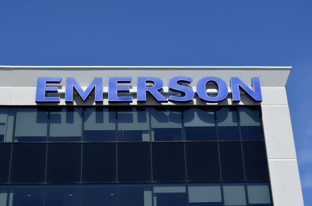 Emerson-Logo an einem Gebäude mit der Aufschrift "1,5 Milliarden Investition in den USA" vor einem klaren blauen Himmel.