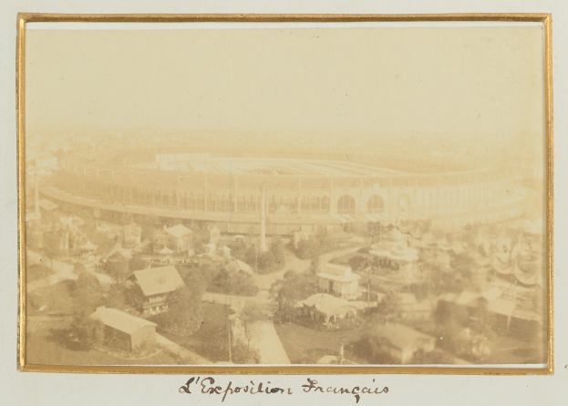 Altes Foto eines Stadions in städtischer Umgebung, umgeben von Gebäuden, Bäumen und Strommasten, mit Text unten.