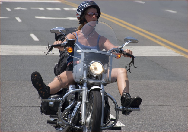 Eine Frau mit schwarzem Helm fährt Fahrrad auf einer Straße.