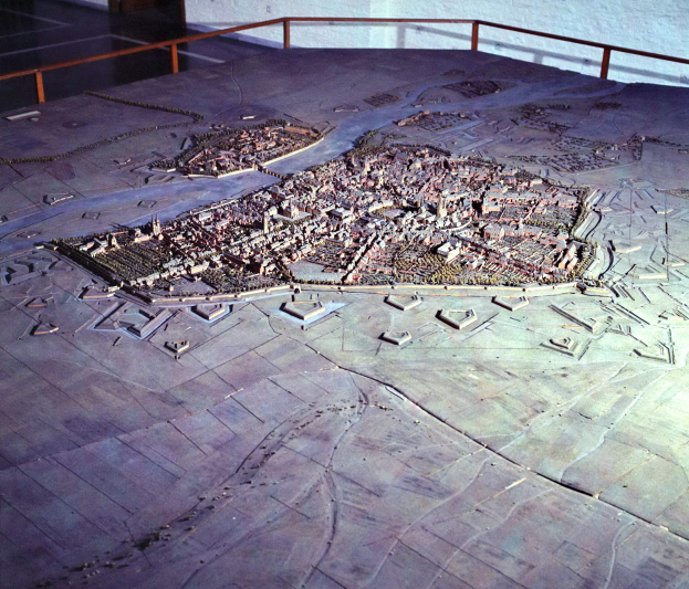 Eine Museumsausstellung mit einem Stadtmodell, einem Boden, einem Geländer und einer Hintergrundwand.