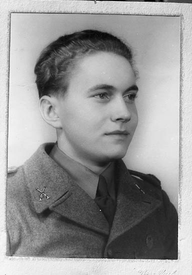 Schwarzes und weißes Foto einer Frau in militärischer Uniform mit ernstem Gesichtsausdruck, die einen Blazer und eine Krawatte trägt, das Haar ordentlich hochgesteckt, konzentrierte Augen und eine selbstbewusste Haltung.