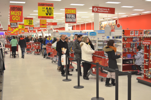 Ein überfüllter Walmart-Laden mit Einkaufstüten tragenden Kunden und Einkaufswagen, mit verschiedenen Auslagen, Schildern und Deckenleuchten im Hintergrund.