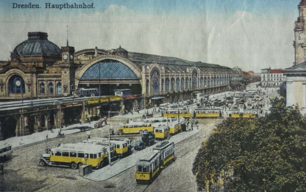 Alte Ansichtskarte des Dresdner Hauptbahnhof-Bahnhofs in Dresden, Deutschland, zeigt eine belebte Straßen Szene mit Fahrzeugen, Fußgängern, Bäumen, Gebäuden und einem bewölkten Himmel.
