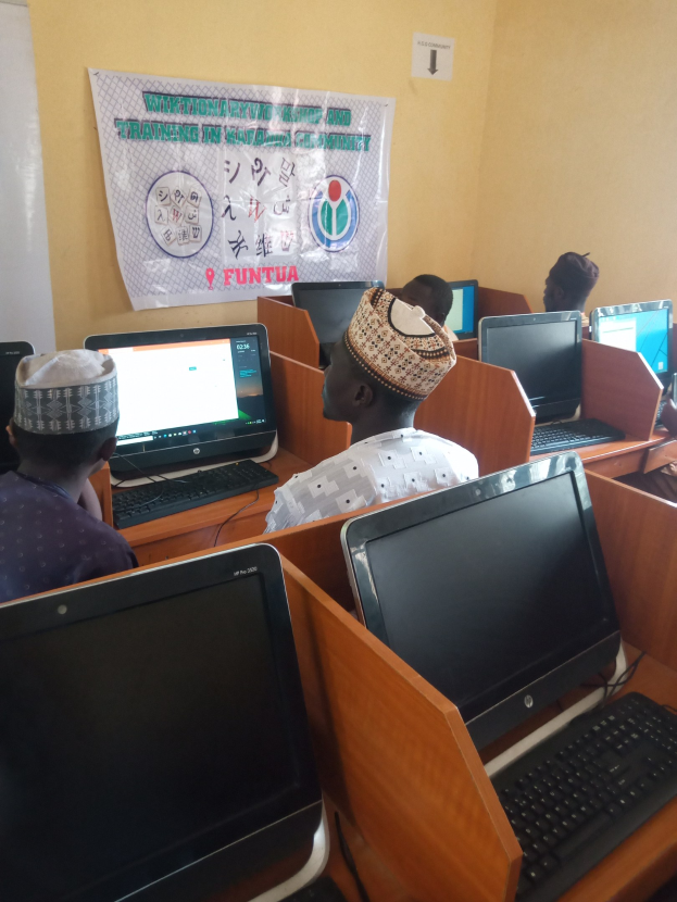Eine Gruppe von Menschen, die an Tischen mit Computern, Tastaturen und Mäusen sitzen und an einem Workshop zur Computertechnologie teilnehmen.